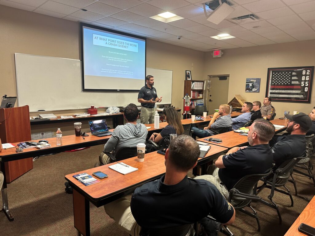 A male instructor leading a class with a projector screen behind him